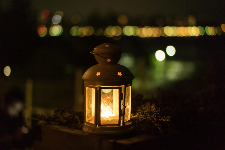 a lantern sitting on top of a wooden post, unsplash, hurufiyya, sweet night ambient, on a candle holder, city lights, soft outdoor light