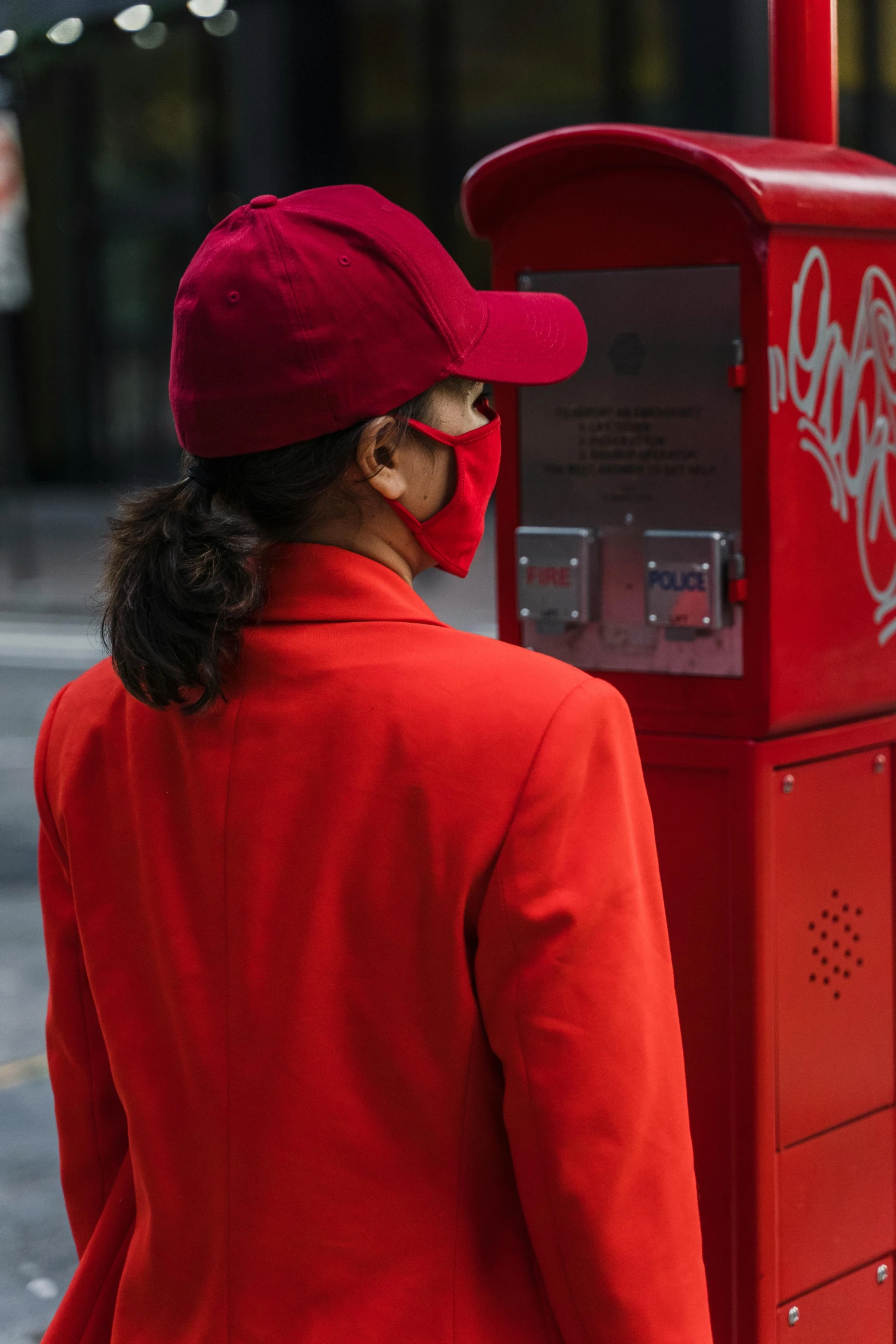 a woman in a red jacket and a red hat, pexels contest winner, private press, vending machine, wearing mask, letterbox, red uniform