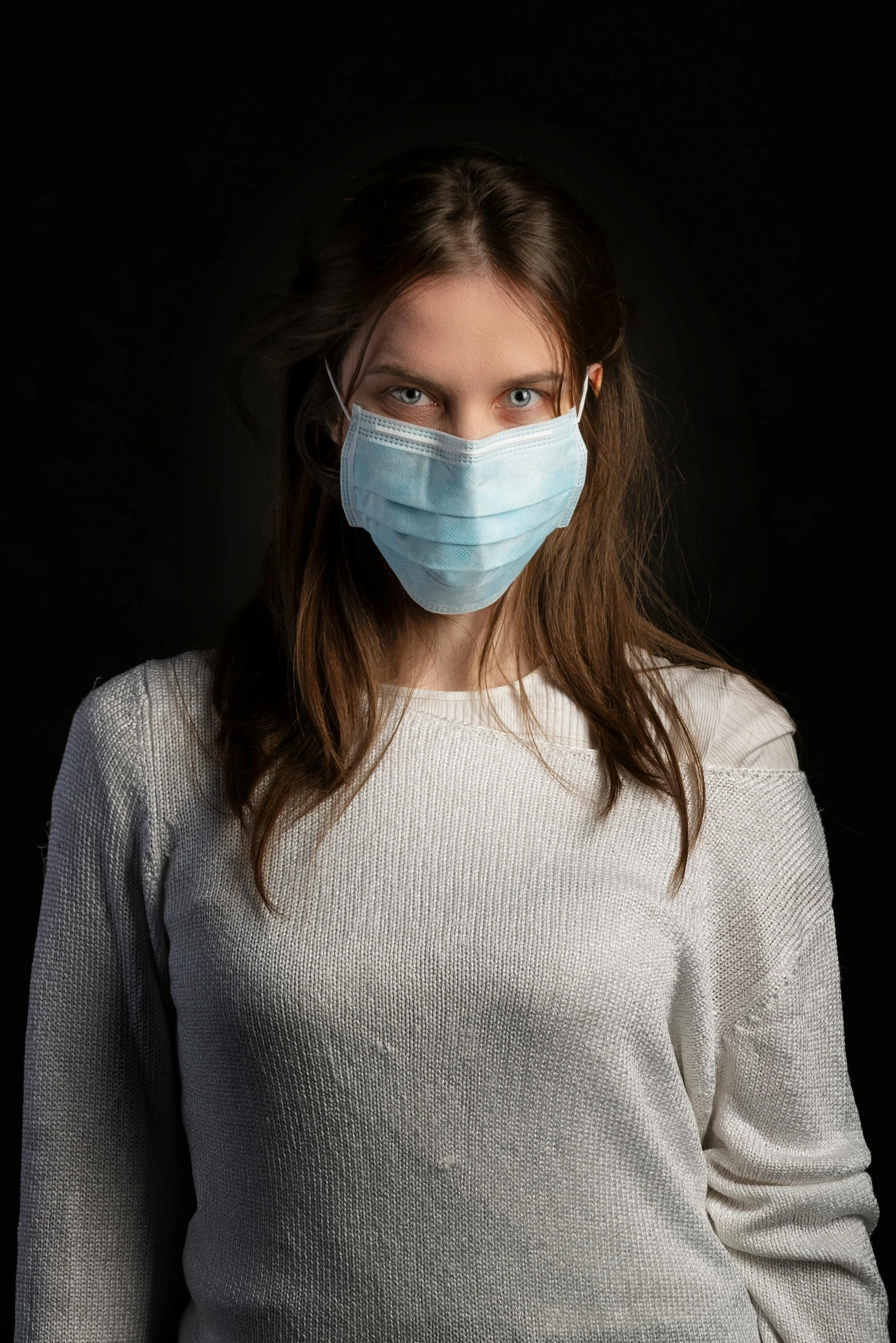 a woman wearing a face mask against a black background, an album cover, by Adam Marczyński, shutterstock, healthcare worker, on a gray background, student, frozen cold stare