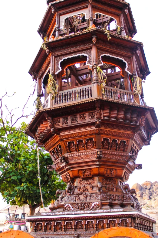 a tall clock tower sitting in the middle of a street, elaborate carved wood balconies, hindu aesthetic, lantern, up-close