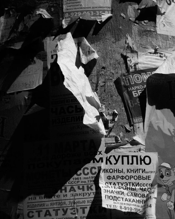 a black and white photo of a telephone pole, a poster, by andrei riabovitchev, unsplash, graffiti, cardboards ; mess, ussr poster, sunlight, magazine scraps