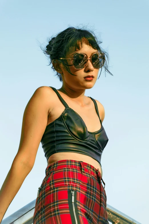 a woman in a black top and red plaid skirt, inspired by Nan Goldin, trending on pexels, wearing leather bikini, blue sky, tank girl, young asian woman