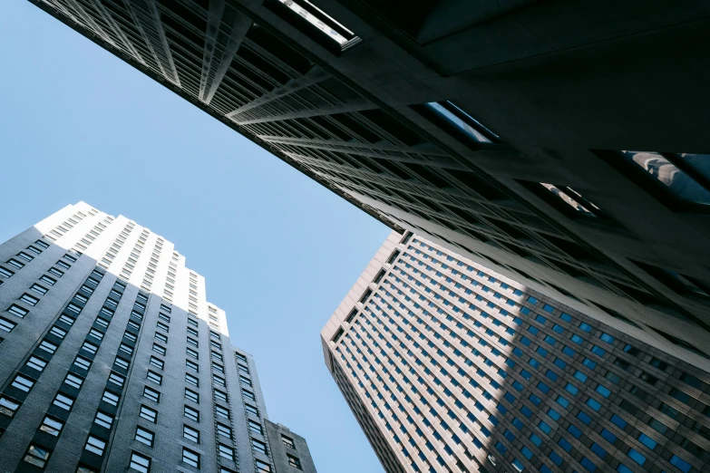 a couple of tall buildings sitting next to each other, by Adam Rex, pexels contest winner, modernism, view from bottom, clear sky above, falling buildings, skybridges