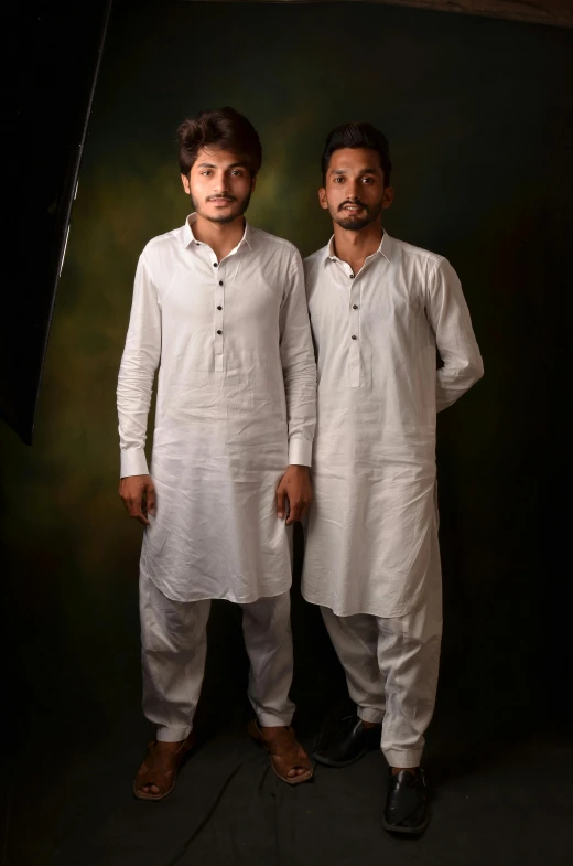 a couple of men standing next to each other, by Riza Abbasi, wearing white pajamas, portrait image, promotional image, traditional clothing