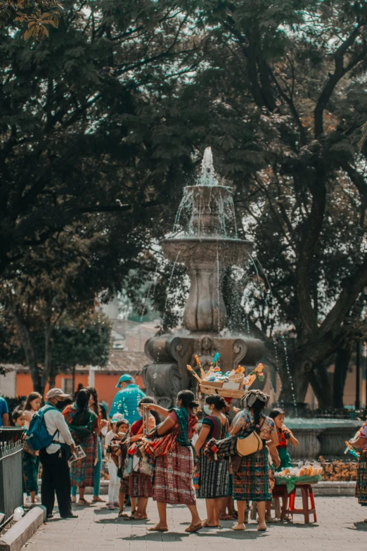 a group of people standing around a fountain, a statue, by Alejandro Obregón, pexels contest winner, tlaquepaque, orange and teal color, central tree, rides
