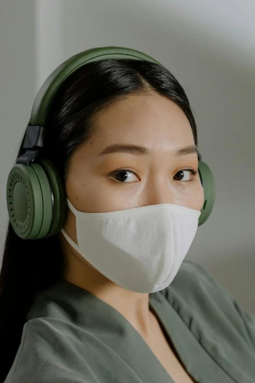 a woman wearing a face mask and headphones, inspired by Feng Zhu, deep green, korean, airscape, zoomed in