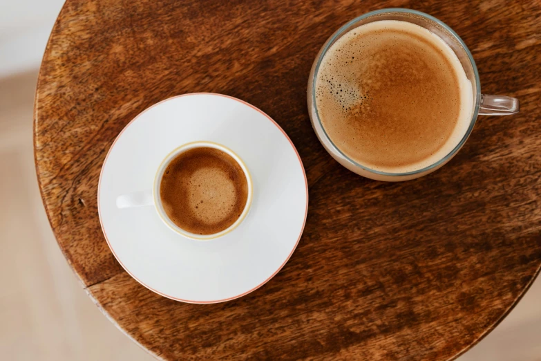 two cups of coffee sitting on top of a wooden table, private press, jen atkin, thumbnail, no cropping, arabica style