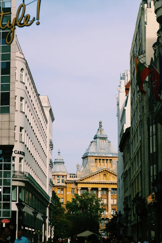 a group of people walking down a street next to tall buildings, inspired by Mihály Munkácsy, unsplash, art nouveau, budapest, stalinist architecture, square, view from bottom
