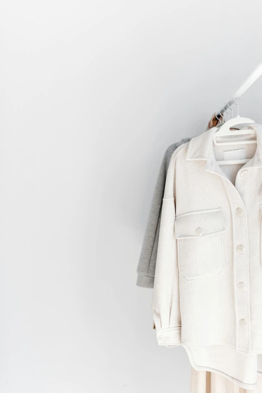 a white shirt hanging on a clothes rack, by Matija Jama, trending on unsplash, minimalism, wearing a white winter coat, silver and muted colors, with a white background, two - tone