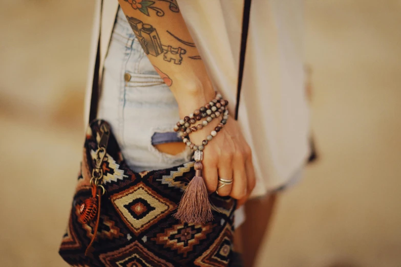 a woman with a tattoo on her arm holding a purse, trending on pexels, dressing tassels gemstones, hippy, wearing casual clothes, 7 0 mm photo