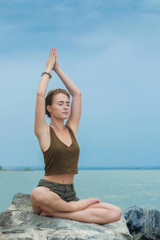 a woman sitting on top of a rock next to the ocean, a statue, an elephant doing yoga poses, square, crossed arms, not cropped