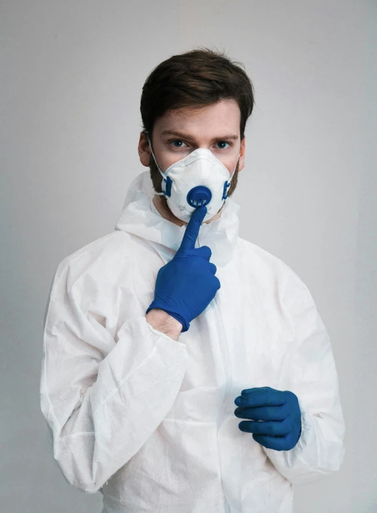 a man wearing a white hazmat suit and blue gloves, trending on reddit, plasticien, hand over mouth, promo image, lookbook, with pointing finger