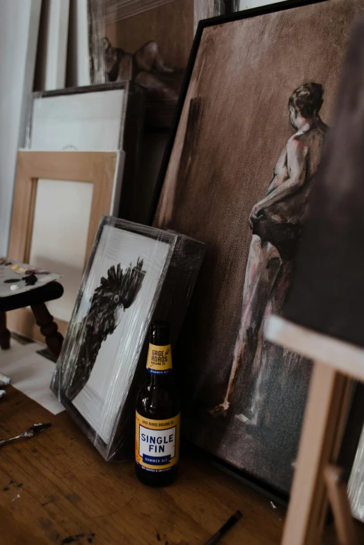 a bottle of beer sitting on top of a wooden table, a photorealistic painting, pexels contest winner, inside a cluttered art studio, photo of a model, whole body in frame, unfinished