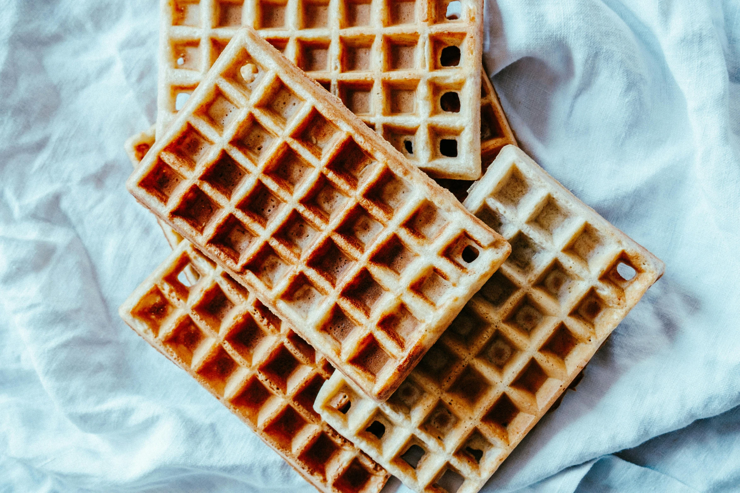 a couple of waffles sitting on top of a table, piled around, grid layout, fan favorite, linen