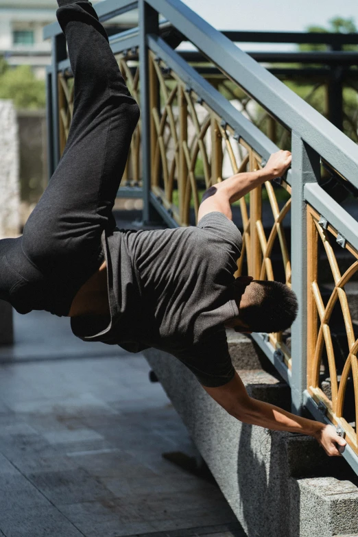 a man flying through the air while riding a skateboard, arabesque, on a bridge, yoga pose, head down, black