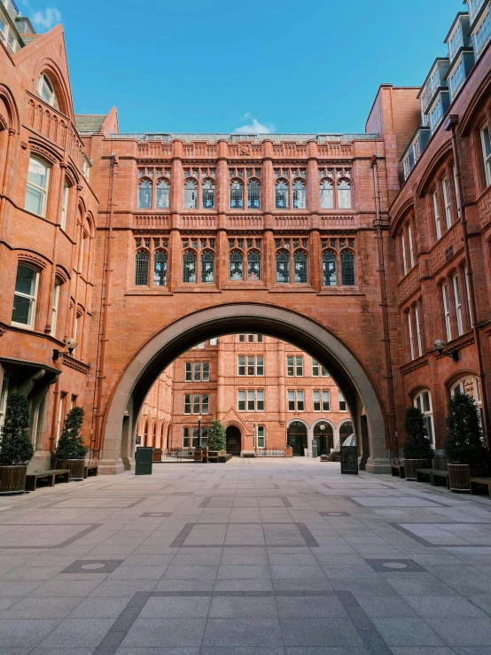 a large brick building with a arch in the middle of it, inspired by Sydney Prior Hall, unsplash contest winner, academic art, manchester, outside the'school of magic ', in style of norman foster, complex buildings