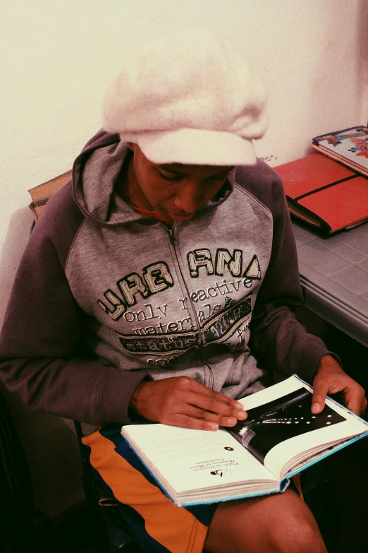 a woman sitting in a chair reading a book, a drawing, instagram, happening, he also wears a grey beanie, afro tech, in a classroom, ivan bolivian