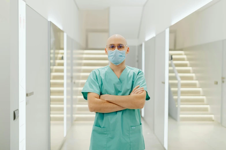 a man wearing a surgical mask standing in a hallway, pexels contest winner, antipodeans, surgical gown and scrubs on, portrait of bald, doctor, sterile colours