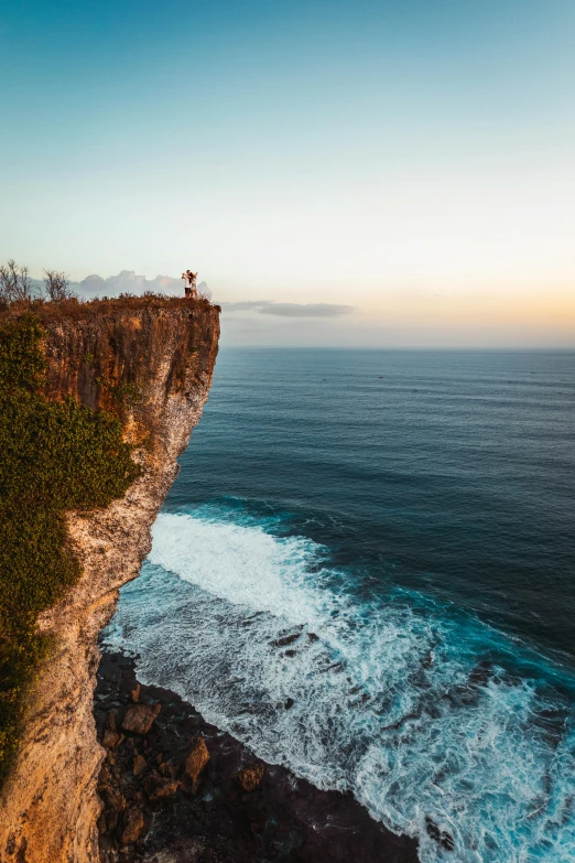 a man standing on the edge of a cliff overlooking the ocean, by Daniel Seghers, pexels contest winner, bali, manly, multiple stories, extreme panoramic