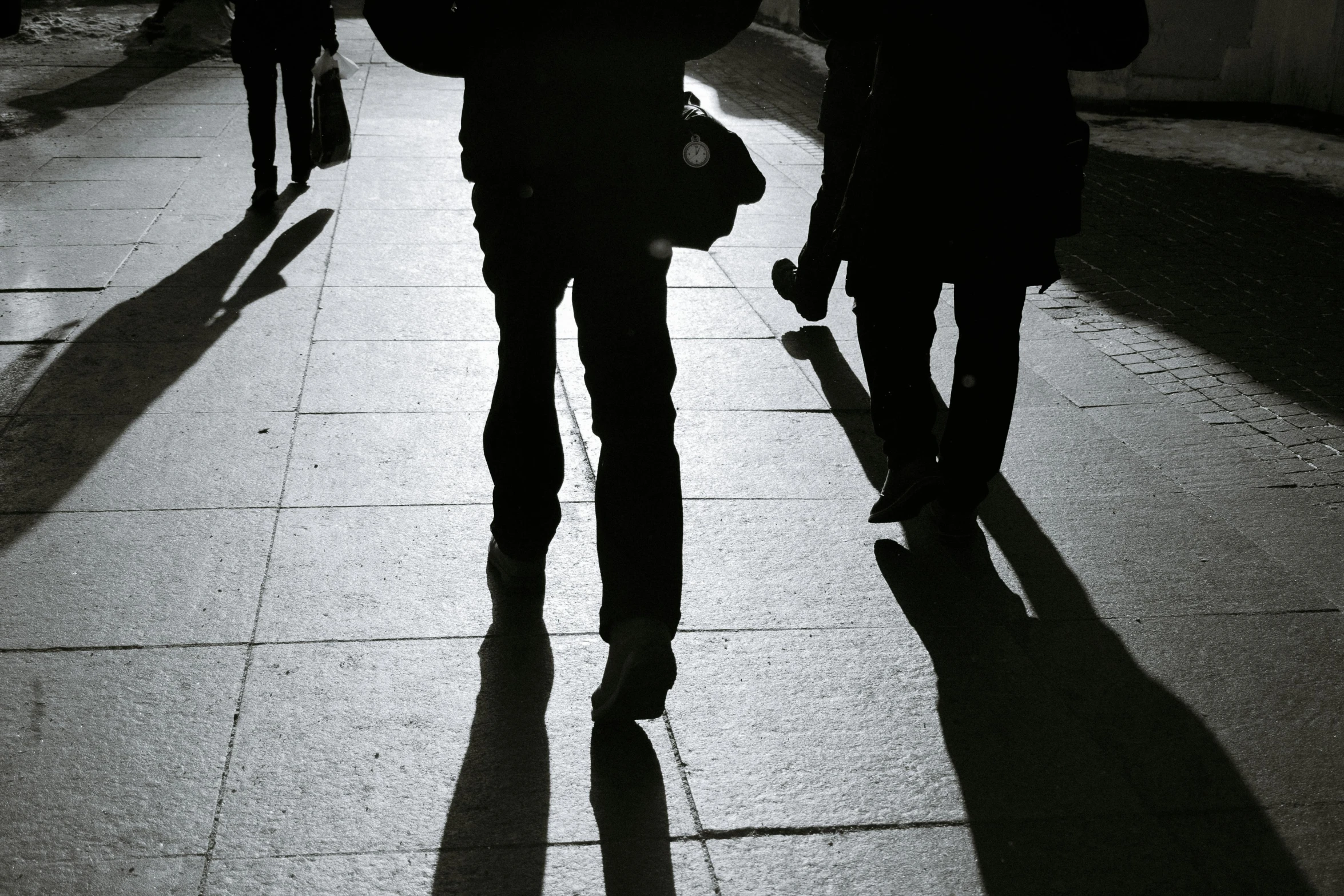 a group of people walking down a sidewalk, a black and white photo, pexels contest winner, realism, shadow gradient, backlit, instagram post, shadowy figures