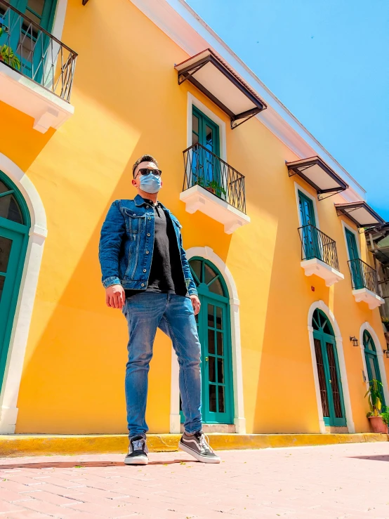 a man standing in front of a yellow building, by Robbie Trevino, avatar image, vacation photo, fullbody photo, background image