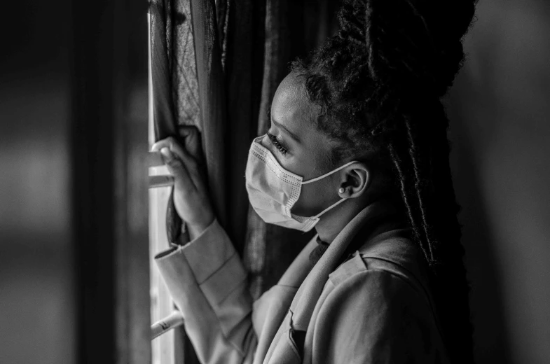 a woman wearing a face mask looking out a window, a black and white photo, african american girl, healthcare worker, lowres, comforting