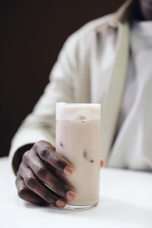 a man sitting at a table with a glass of milk, an album cover, inspired by Theo Constanté, unsplash, hurufiyya, drink milkshakes together, light-brown skin, closeup portrait, somalia