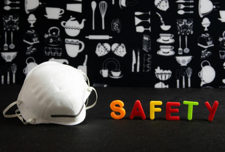 a hat sitting on top of a table next to a safety sign, with a black background, toys, cuisine, white mask