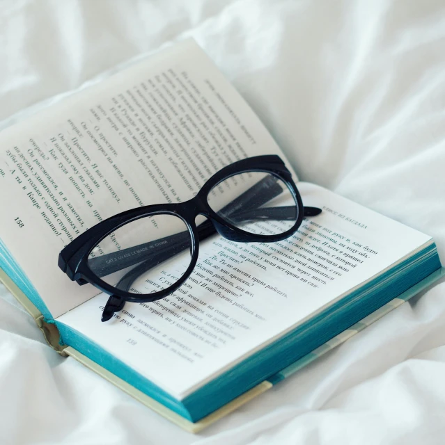 a pair of glasses sitting on top of an open book