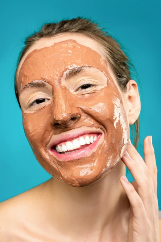 a woman with a mud mask on her face, by Julia Pishtar, shutterstock, antipodeans, she is smiling and excited, wearing a brown, brown:-2, candy treatments