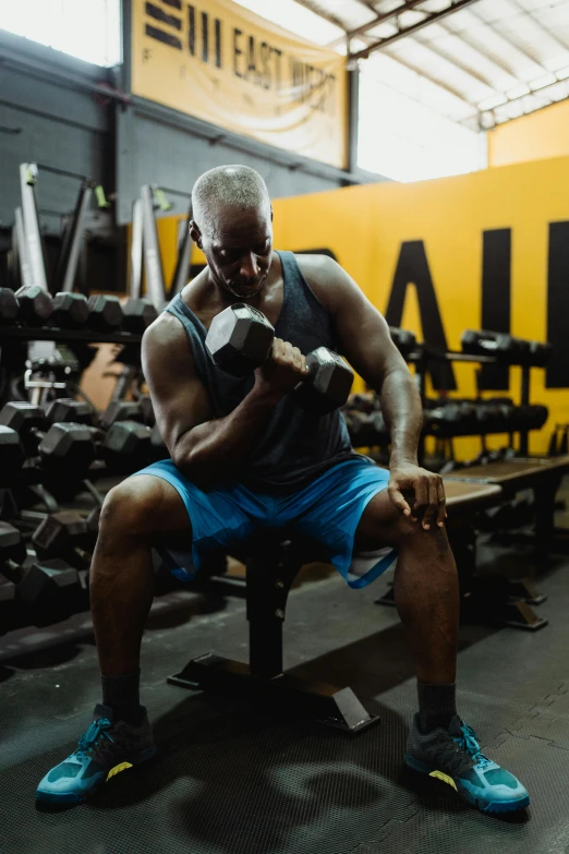 a man sitting on a bench in a gym, holding a hammer, profile image, black man, 2019 trending photo