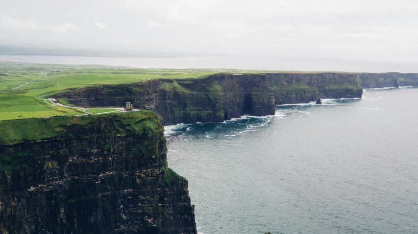 a man standing on top of a cliff next to the ocean, pexels contest winner, renaissance, ancient irish, photo of green river, taken in the 2000s, from of thrones