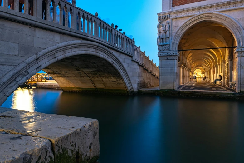 a bridge over a body of water next to a building, by Carlo Martini, unsplash contest winner, renaissance, calm evening, sweeping arches, profile picture 1024px, prussian blue and venetian red