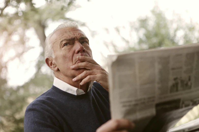 a man sitting on a bench reading a newspaper, a picture, pexels, private press, looking surprised, an oldman, looking upwards, reading under a tree