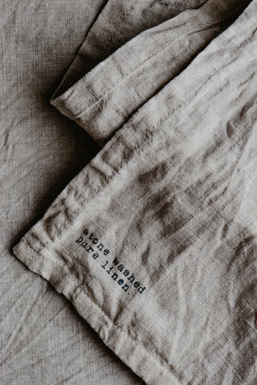 a pair of pants sitting on top of a bed, an album cover, inspired by Jakob Häne, unsplash, minimalism, etched inscriptions, linen, close up high detailed, tablecloth