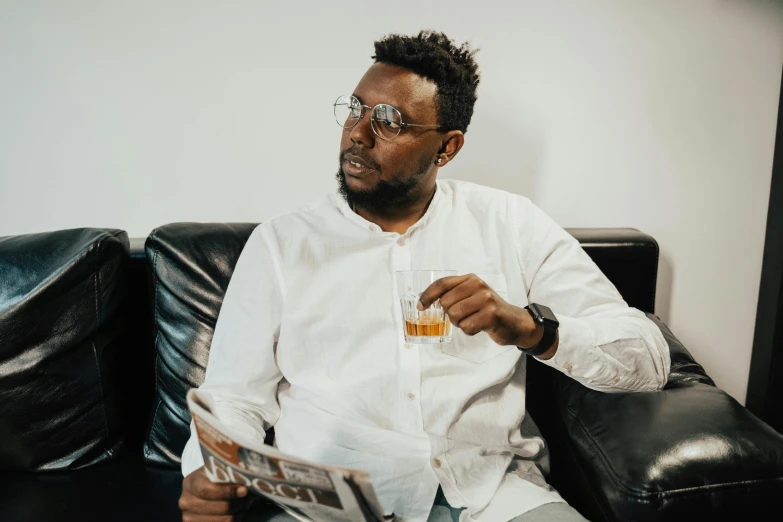 a man sitting on a couch reading a newspaper, an album cover, pexels contest winner, hurufiyya, wearing a white button up shirt, drinking whiskey, avatar image, wearing square glasses