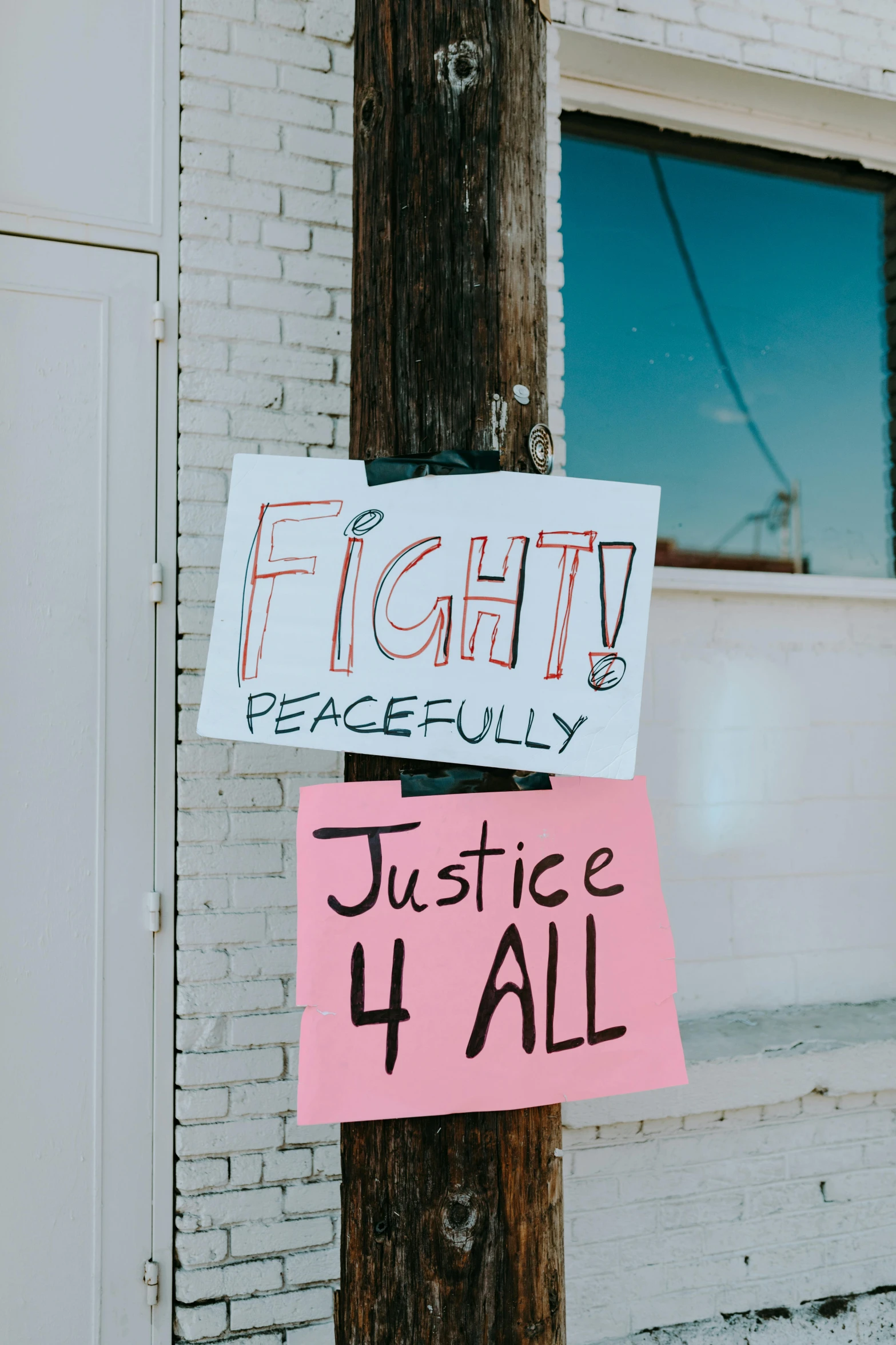 a pole with a sign on it that says fight peacefully justice it all, by Grace Polit, pexels, placards, four, winning artwork, essence