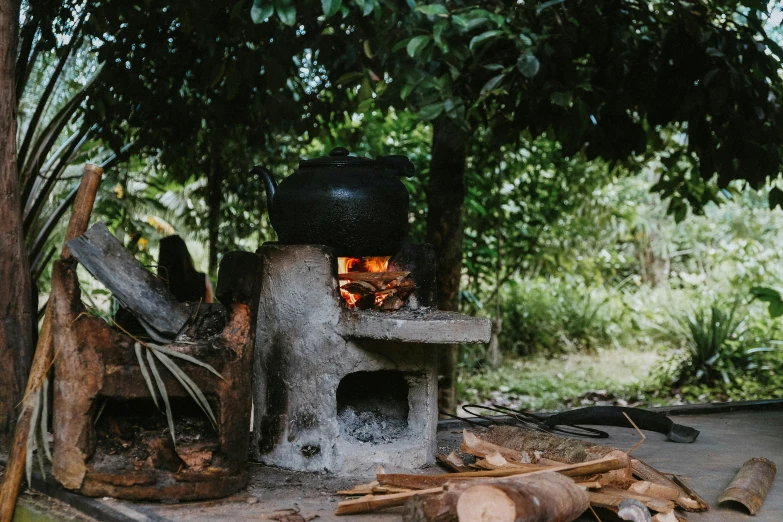 a pot sitting on top of a stove next to a pile of wood, by Daniel Lieske, pexels contest winner, hurufiyya, in the jungle, oven, outside in a farm, thumbnail