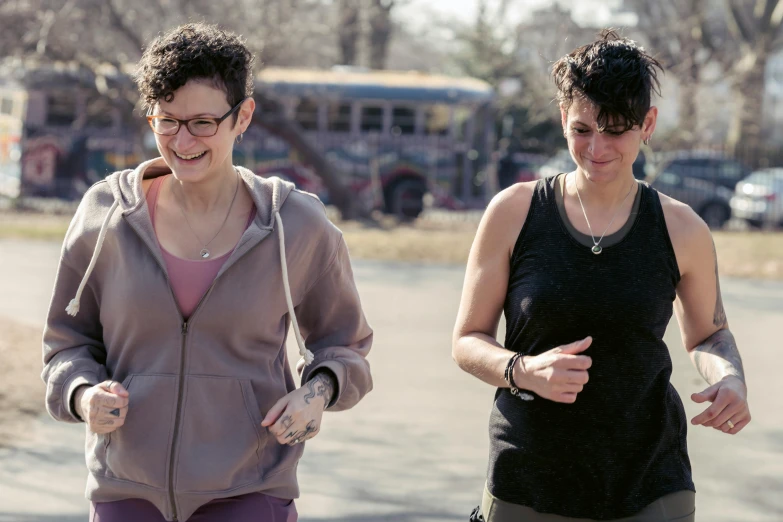 a couple of women standing next to each other on a street, zachary corzine, pacing, lynn skordal, park in background