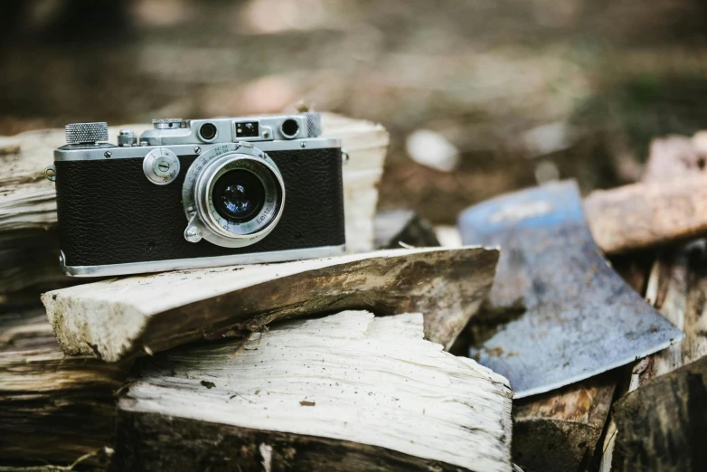 a camera sitting on top of a pile of wood, a picture, by Peter Churcher, unsplash, leica iii, grey metal body, hunting, small