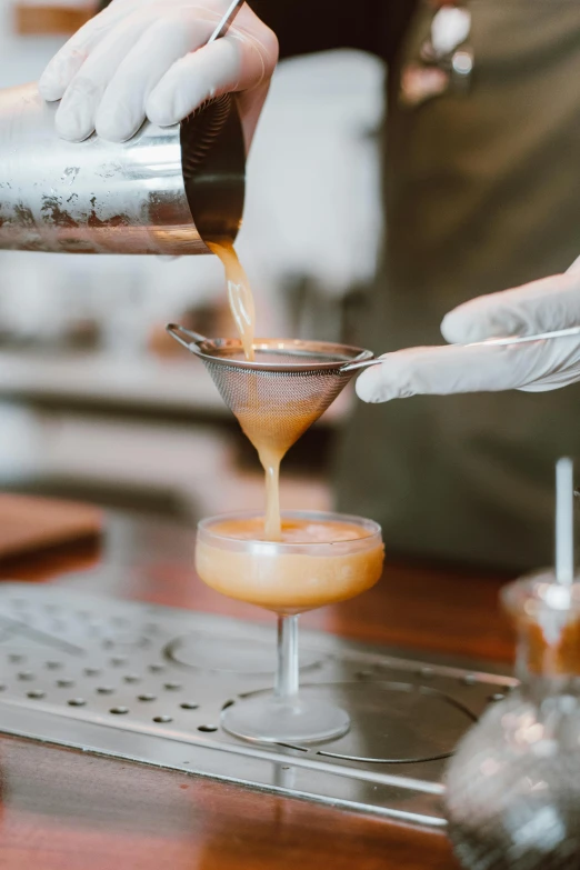 a person pouring a drink into a glass, cone shaped, mid riff, cooked, blended