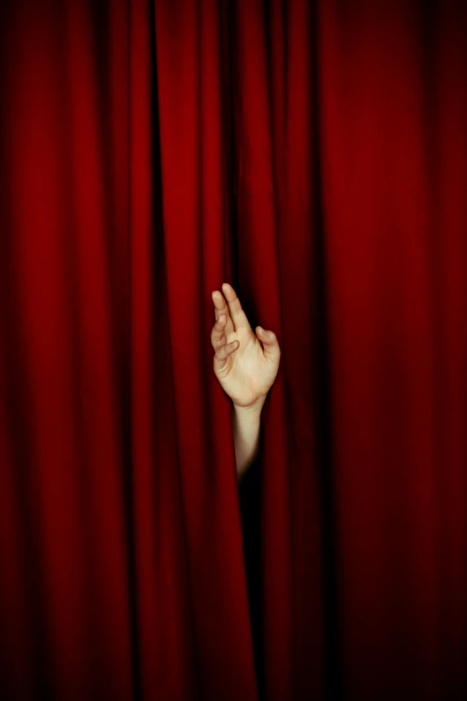 a hand reaching out from behind a red curtain, by Alison Geissler, aestheticism, pareidolia, award - winning photo ”, ultra - realism, theater