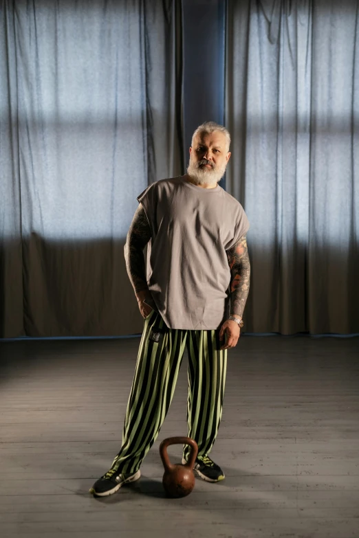 a man standing in a room with a kettle, inspired by Lajos Vajda, renaissance, wearing a baggy pajamas, old gigachad with grey beard, production photo, stripey pants