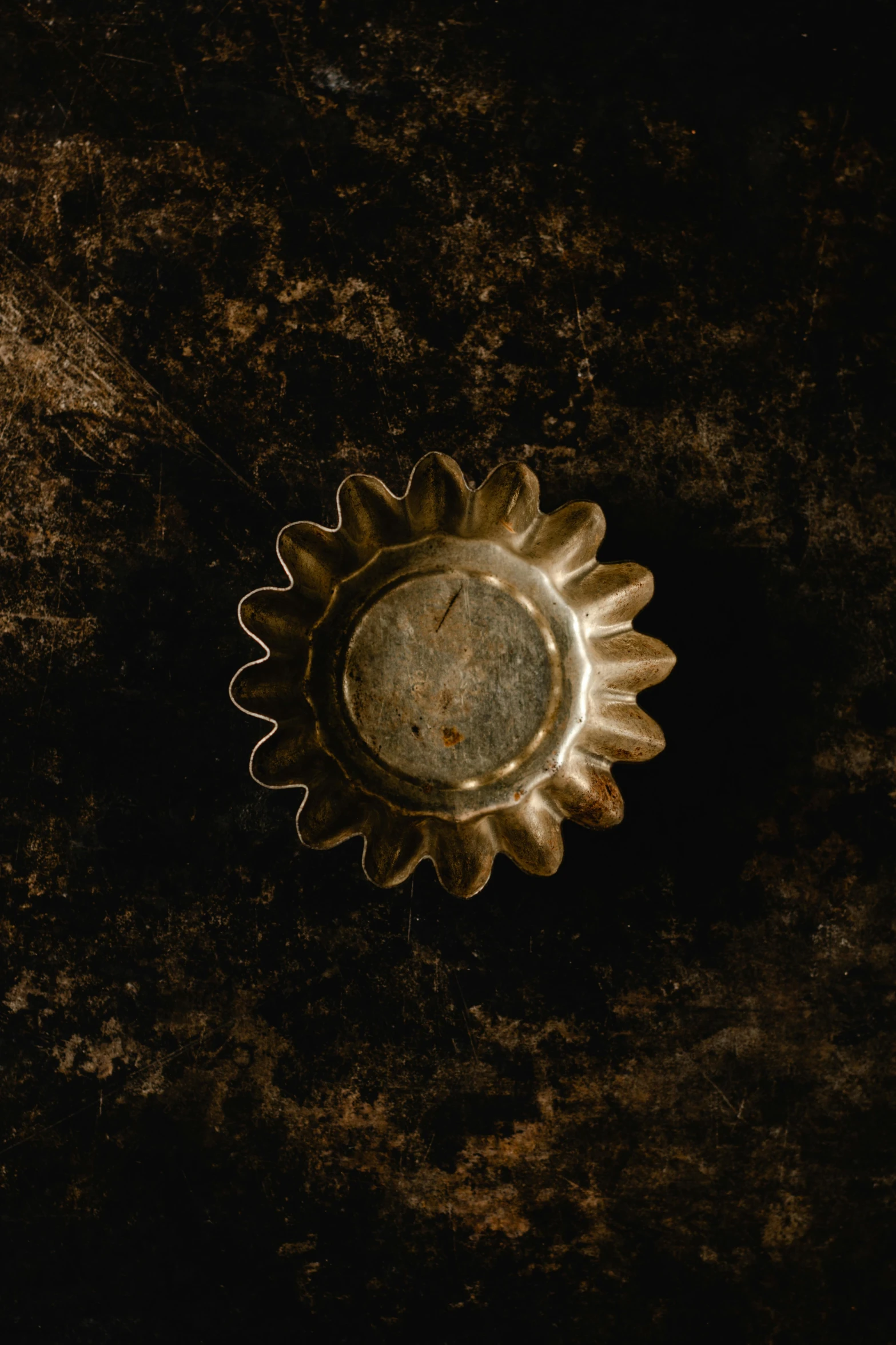 a close up of a metal object on a surface, an album cover, inspired by Anna Füssli, trending on unsplash, baroque, dark sun, detailed product image, bottom view, made of bronze