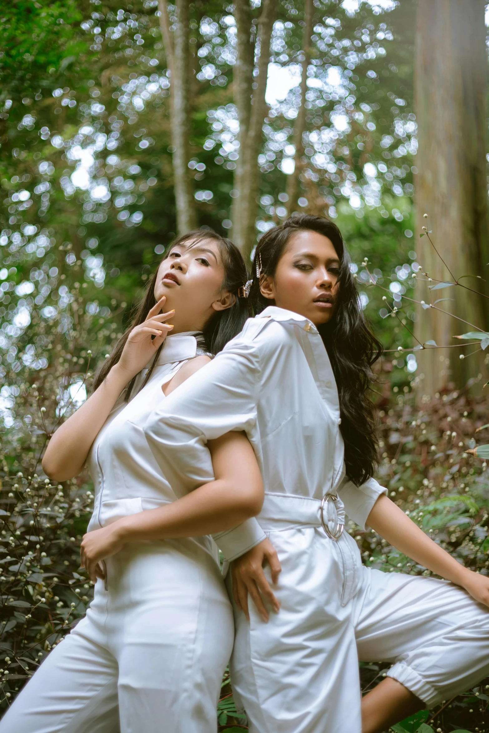 a couple of women standing next to each other in a forest, an album cover, inspired by Wang Duo, unsplash, sumatraism, wearing white pajamas, sassy pose, studio photo, indonesia