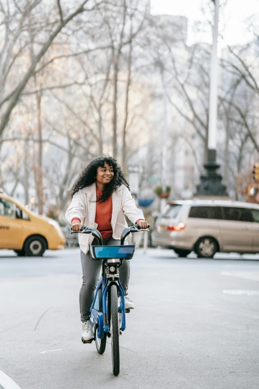 a woman riding a bike on a city street, blue, in new york city, square, ashteroth