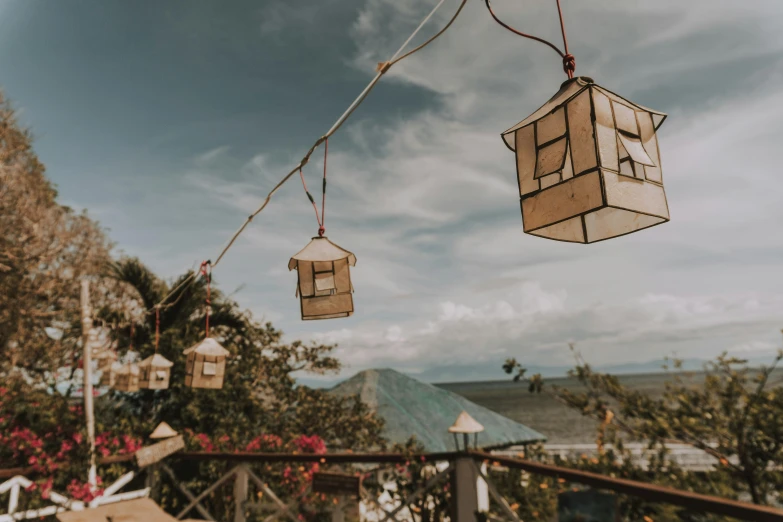 a couple of bird houses hanging from a string, an album cover, trending on unsplash, happening, golden hour in boracay, cafe lighting, rooftop party, lanterns