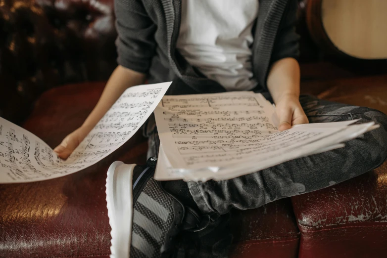 a person sitting on a couch holding a sheet of music, pexels, school, lachlan bailey, 15081959 21121991 01012000 4k, soft vinyl