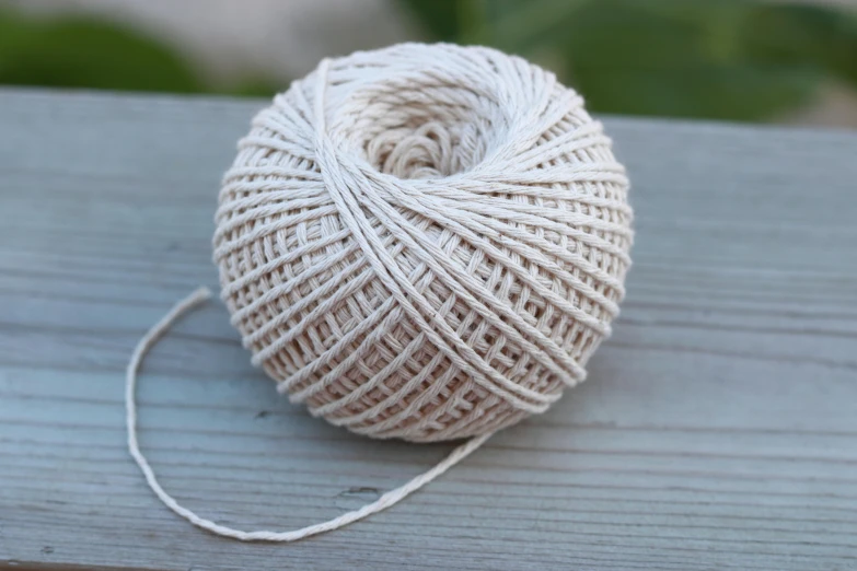 a ball of yarn sitting on top of a wooden table, limestone, in the sun, detailed product image, small