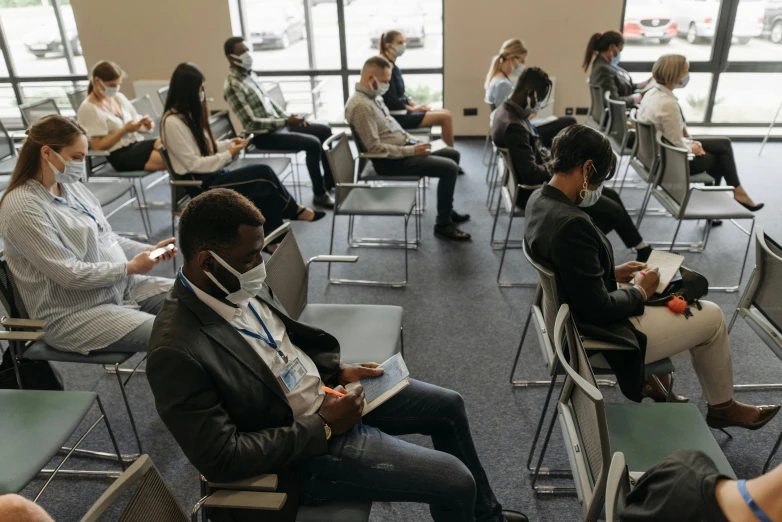 a group of people sitting in chairs in a room, standing in class, people are wearing masks, profile image, high angle